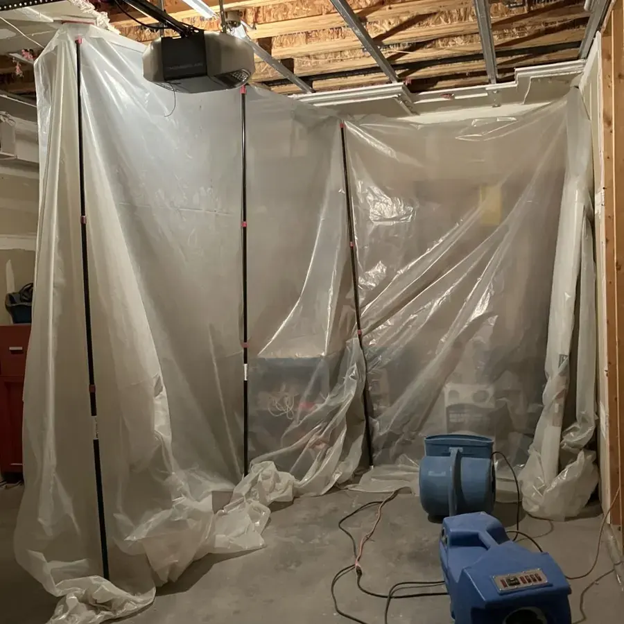 Plastic containment and an air mover set up in an unfinished basement